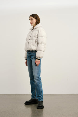 A model wearing a light gray puffer jacket paired with blue jeans and black boots, showcasing MEOTINE's stylish outerwear.