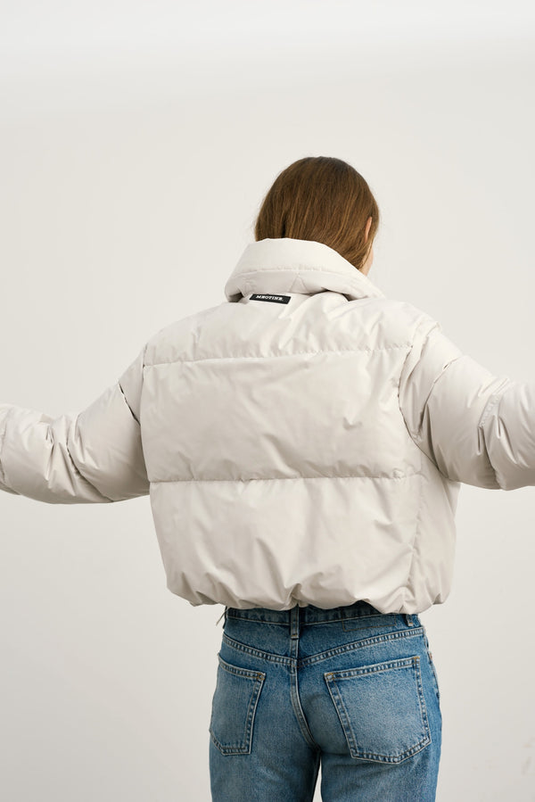 A model showcases a stylish MEOTINE puffer jacket from the back, featuring a cropped design and relaxed fit, paired with jeans.