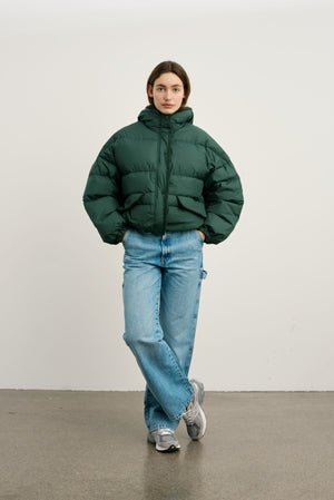 A model wears a stylish green puffer jacket paired with relaxed-fit jeans, showcasing MEOTINE's trendy winter fashion.