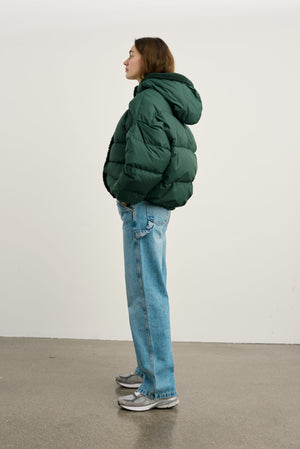 A model showcases a green puffer jacket paired with light blue jeans and sneakers, embodying a casual, stylish look by MEOTINE.