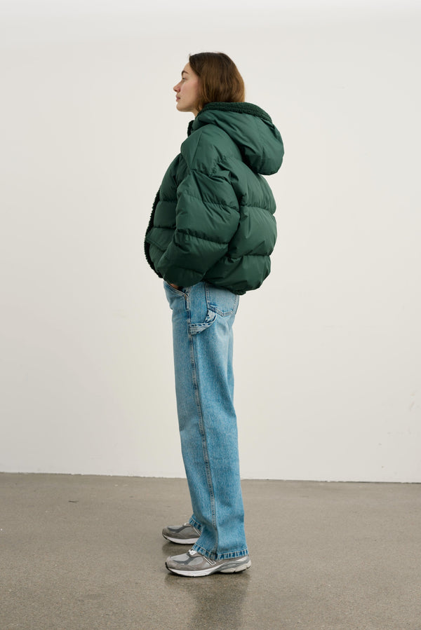A model showcases a green puffer jacket paired with light blue jeans and sneakers, embodying a casual, stylish look by MEOTINE.