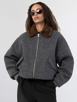 Stylish gray bomber jacket with a brown fur collar, worn by a model with curly hair and sunglasses, showcasing MEOTINE's chic design.