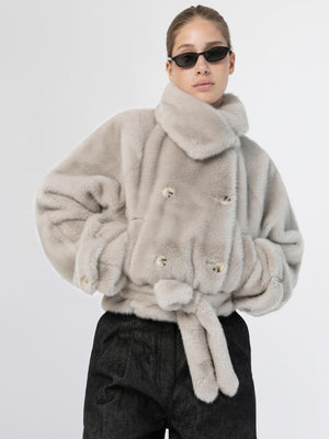 Cozy beige faux fur jacket with a double-breasted design and tie waist, styled with sleek sunglasses. MEOTINE brand.