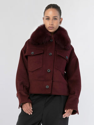 A model showcases a stylish burgundy jacket with a fur collar, featuring large pockets and a relaxed fit, by MEOTINE.
