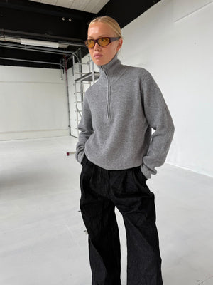 A model wears a gray zip-up sweater and black wide-leg pants, showcasing a stylish, casual look by MEOTINE.