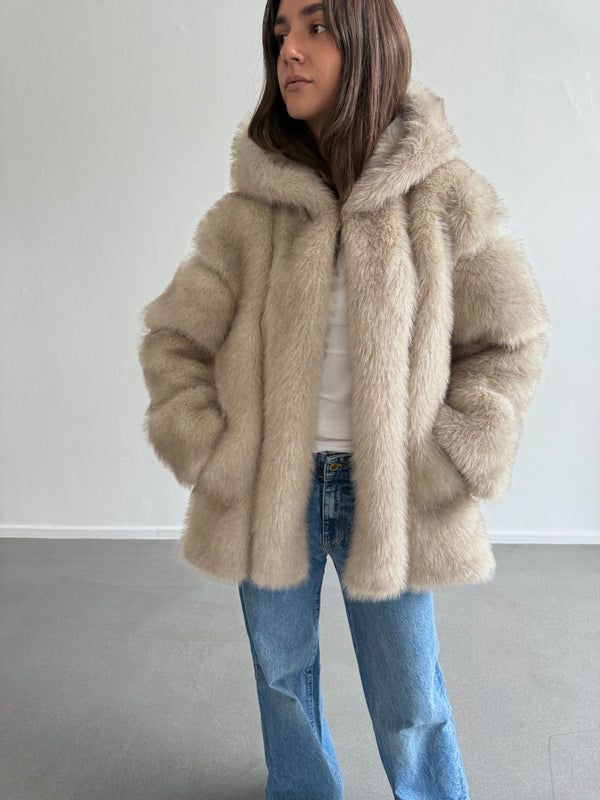 A model wearing a cozy beige faux fur jacket with a hood, paired with light blue jeans, showcasing MEOTINE's stylish design.