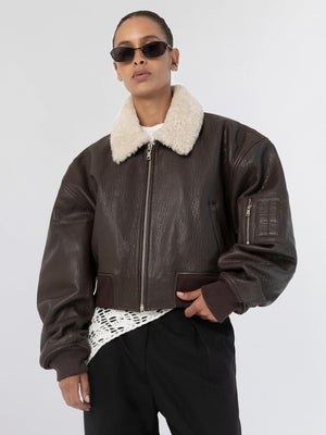 Brown leather cropped jacket with a plush collar, styled with sunglasses and a casual outfit, showcasing MEOTINE's unique design.