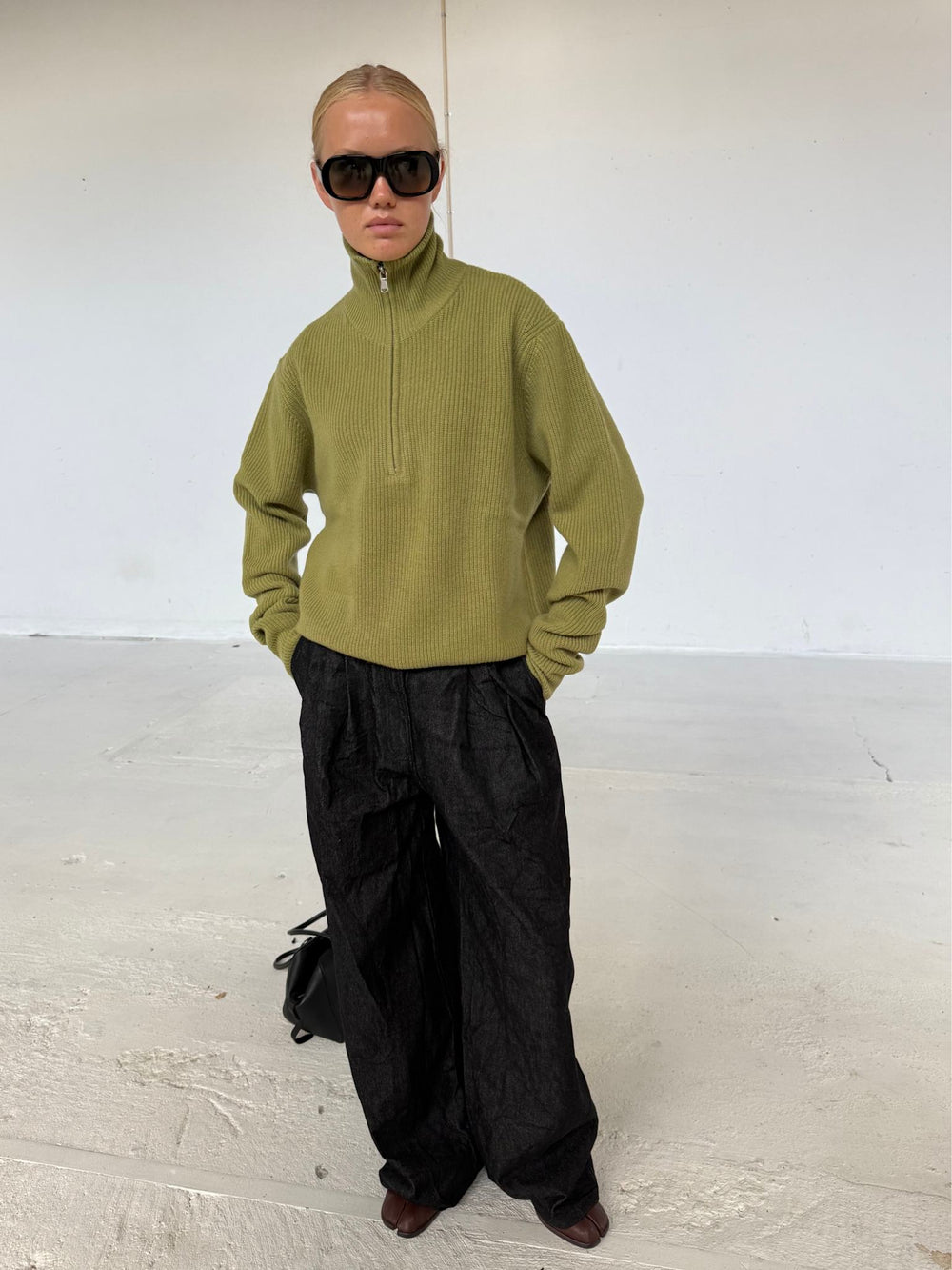 A model wears a stylish olive green ribbed sweater with a high collar and oversized black sunglasses, showcasing MEOTINE's chic design.