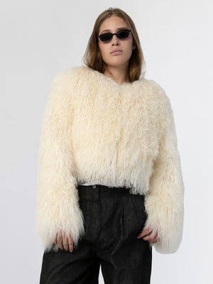 Cozy cream-colored fluffy sweater with oversized sleeves, styled with dark high-waisted pants and sunglasses, by MEOTINE.