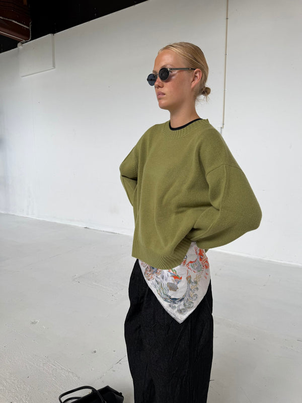 A model showcases a stylish green sweater paired with a floral scarf and black pants, embodying MEOTINE's chic aesthetic.