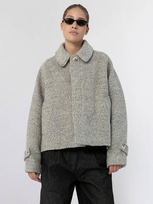A model wears a stylish, cropped gray jacket with a collar and button details, showcasing MEOTINE's contemporary design.