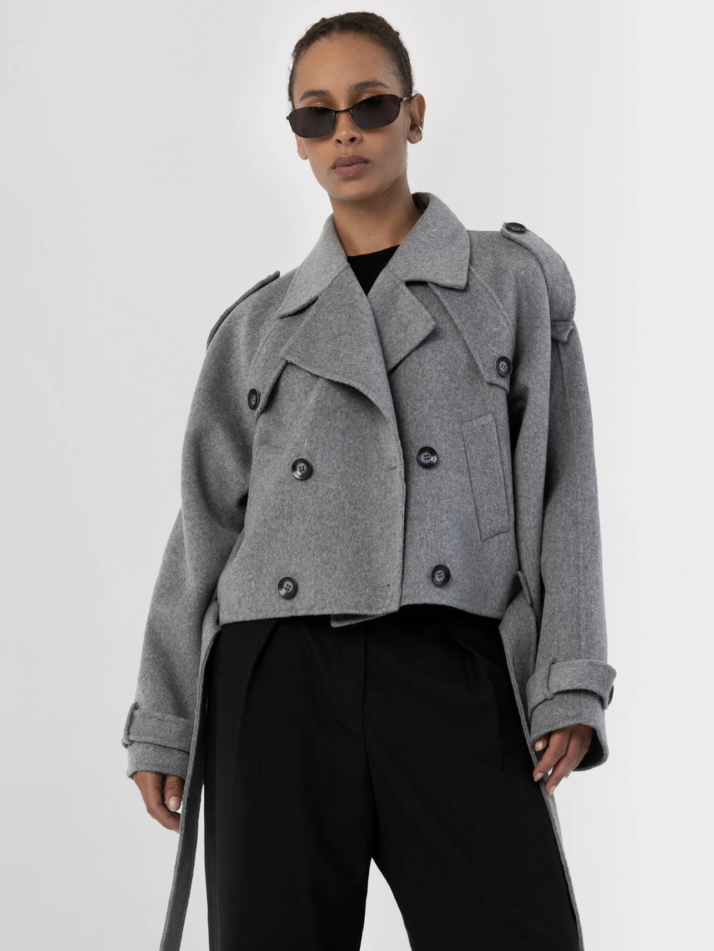 Stylish gray cropped trench coat with double-breasted buttons, paired with sleek black pants and sunglasses, by MEOTINE.