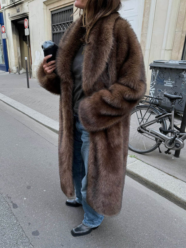 A woman wearing a luxurious brown fur coat, styled with casual jeans and black boots, exuding elegance and warmth. MEOTINE.