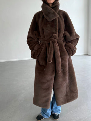 Cozy brown faux fur coat with a belted waist, featuring a high collar, worn over casual jeans and black shoes. MEOTINE.