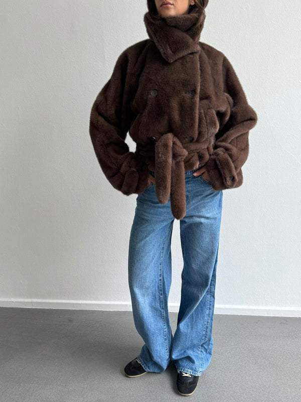 Cozy brown faux fur jacket with a belted waist, paired with wide-leg blue jeans, showcasing a stylish, relaxed look by MEOTINE.