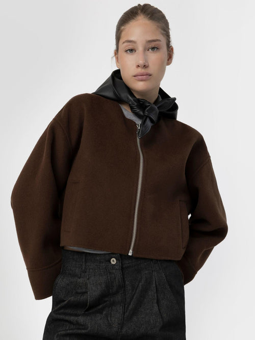 A model wears a stylish brown cropped jacket with a zip and a black scarf, showcasing MEOTINE's modern design.