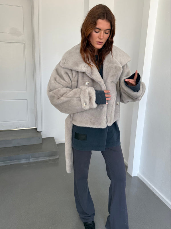 A model showcases a cozy, oversized gray faux fur jacket from MEOTINE, paired with a dark top and relaxed pants.