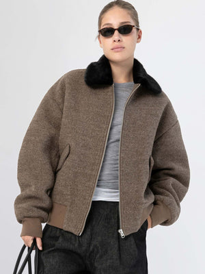 A model wears a stylish brown bomber jacket with a black fur collar, paired with a gray top and dark pants, showcasing MEOTINE's chic design.