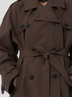 A stylish brown trench coat with a belted waist and double-breasted buttons, perfect for a chic look by MEOTINE.