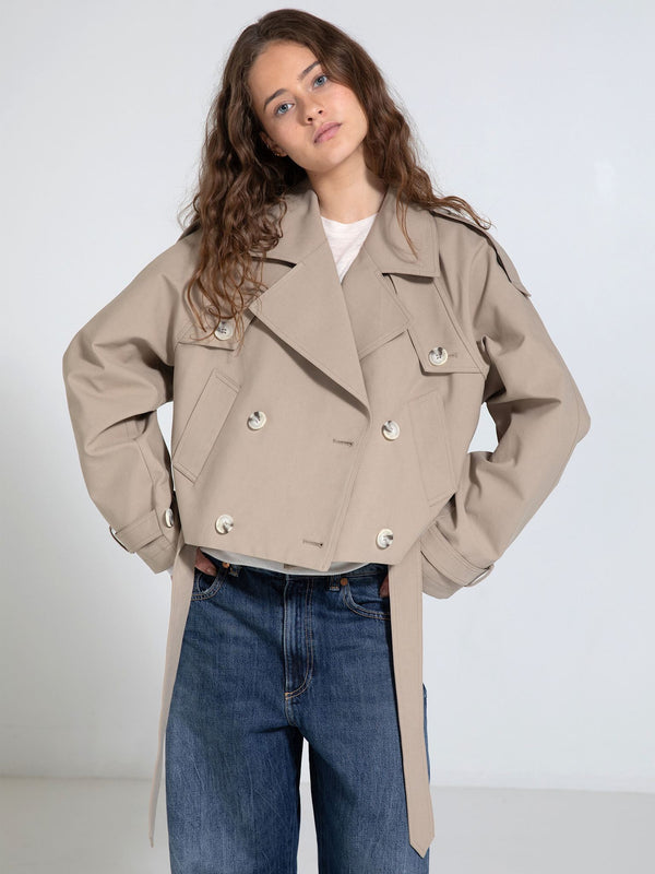 A model poses in a stylish beige cropped trench coat with a double-breasted design, showcasing MEOTINE's modern aesthetic.