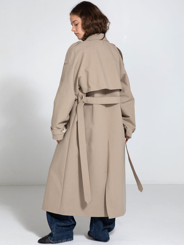 A model showcases a stylish beige trench coat with a belted waist, designed by MEOTINE, perfect for a chic, modern look.