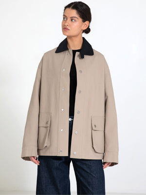 A model showcases a beige MEOTINE jacket with a black collar, featuring large front pockets and a relaxed fit.