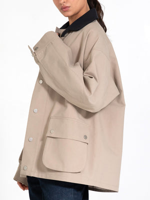 A model showcases a stylish beige MEOTINE jacket with a black collar and a large front pocket, perfect for a casual look.