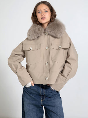 A model showcases a stylish beige cropped jacket with a plush fur collar, paired with relaxed denim jeans. MEOTINE brand.
