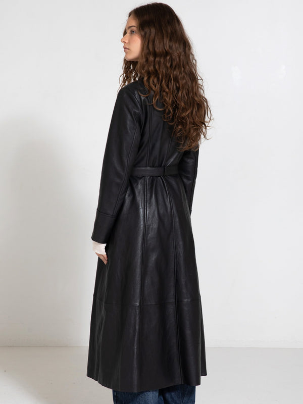 A model showcases a stylish black leather coat with a belted waist, exuding elegance and sophistication by MEOTINE.