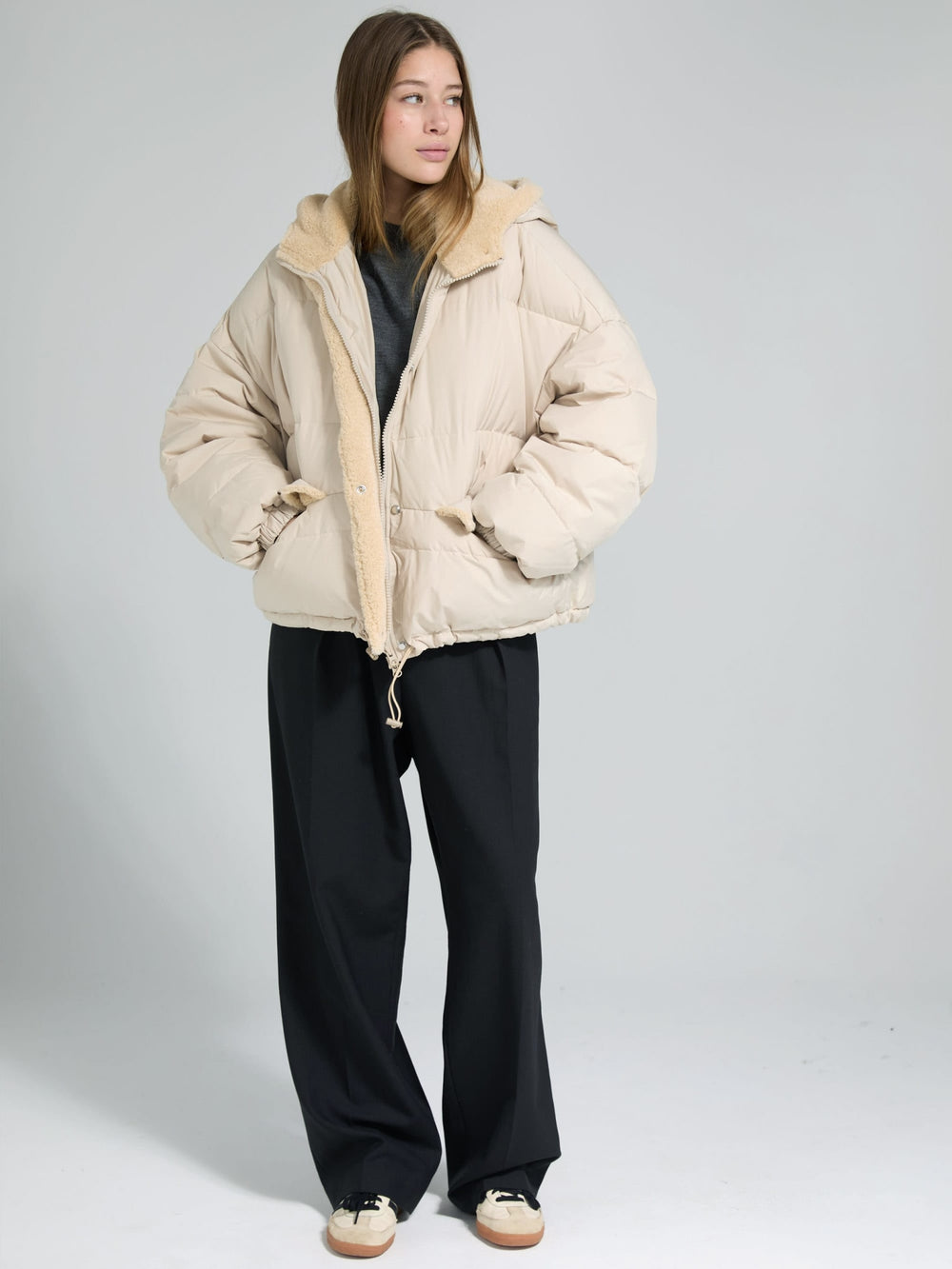 A model wears a cozy beige MEOTINE puffer jacket with a soft fur collar, paired with a gray top and black pants.