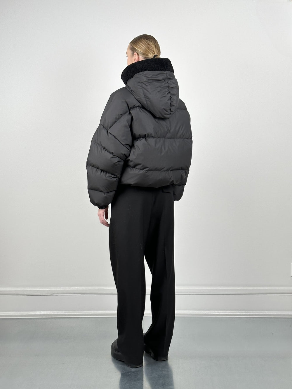 Stylish black puffer jacket with a hood, paired with high-waisted black trousers, showcasing MEOTINE's modern winter fashion.