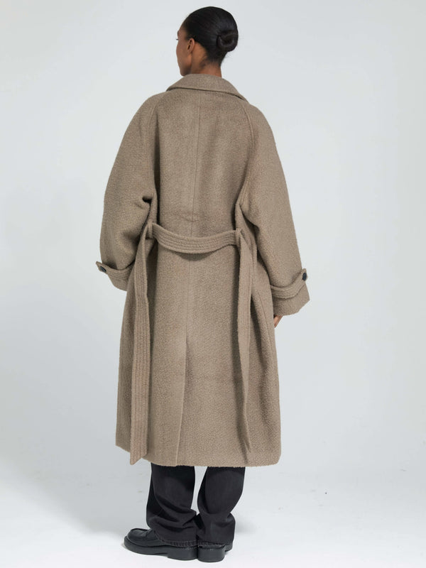 A model wearing a cozy, oversized brown coat with a belt, showcasing a relaxed fit and stylish design by MEOTINE.