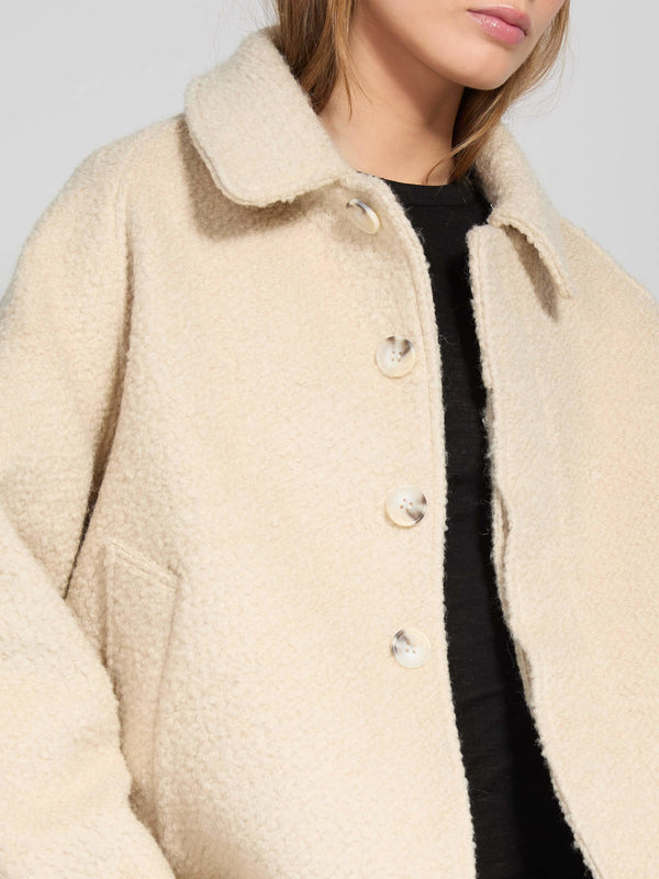 A model wears a cozy beige MEOTINE jacket with a collared neckline and button closure, perfect for stylish layering.