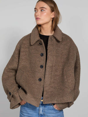 A model wears a cozy brown MEOTINE jacket with a relaxed fit, featuring a collared neckline and button closure, styled with jeans.