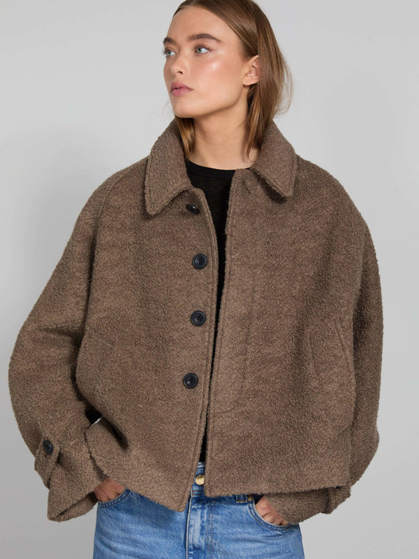 A model wears a cozy brown MEOTINE jacket with a relaxed fit, featuring a collared neckline and button closure, styled with jeans.