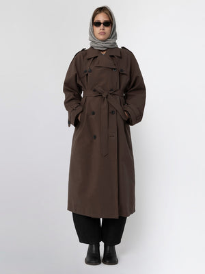 A model wearing a brown trench coat with a belt, paired with a gray scarf and sunglasses, showcasing MEOTINE's stylish outerwear.