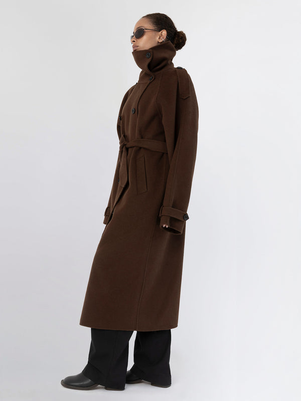 A model showcases a stylish brown long coat with a high collar and belt, paired with sleek black pants and sunglasses. MEOTINE.