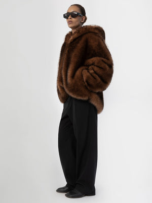 A model showcases a luxurious brown faux fur coat by MEOTINE, paired with oversized sunglasses and wide-leg black trousers.
