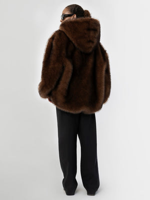 A model wearing a luxurious brown faux fur coat with a hood, paired with black wide-leg pants, showcasing MEOTINE's elegant style.