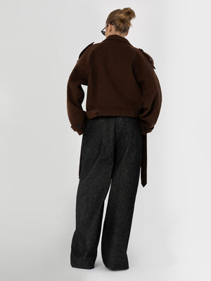 A model wearing a brown oversized jacket and dark wide-leg pants, showcasing a stylish and contemporary look by MEOTINE.