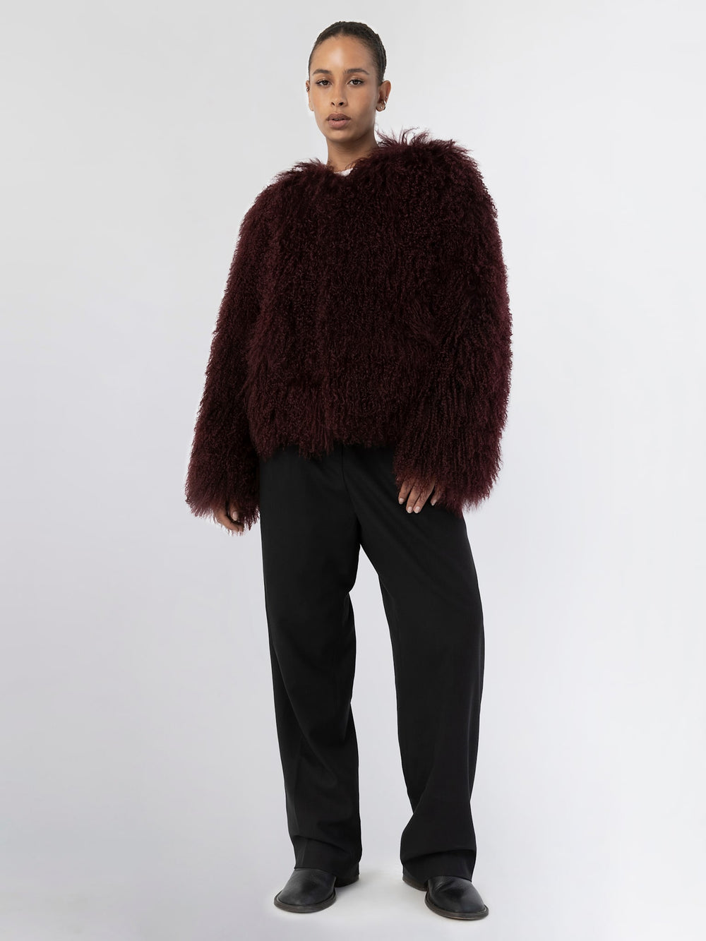 A model showcases a plush, burgundy MEOTINE jacket paired with light blue flared jeans, exuding a cozy, stylish vibe.