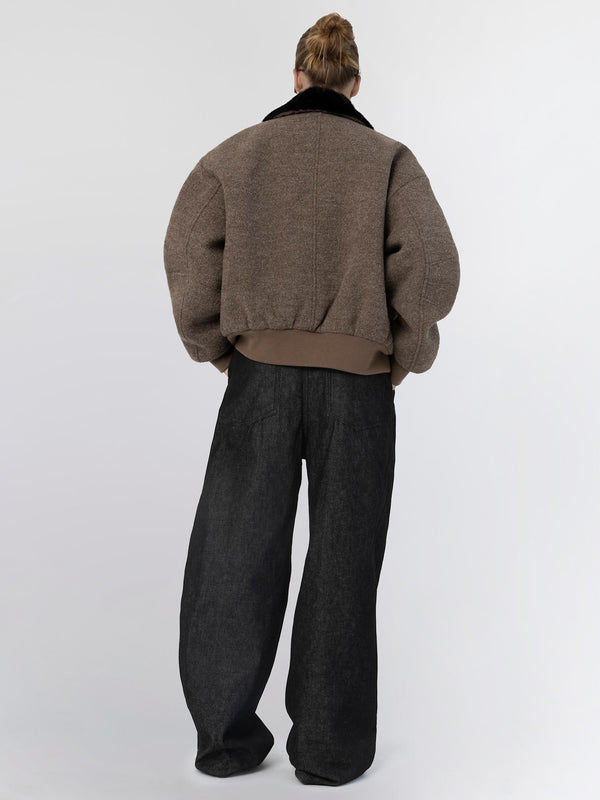 Oversized brown jacket with a black collar, paired with loose black pants, showcasing a relaxed, modern style by MEOTINE.