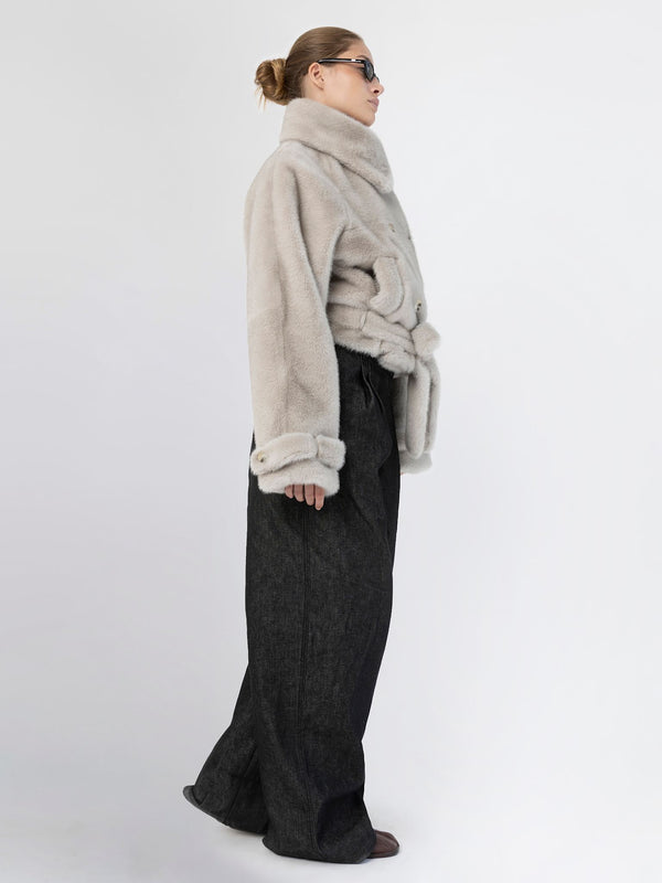 A model showcases a stylish MEOTINE oversized faux fur jacket paired with wide-leg black trousers, exuding modern elegance.