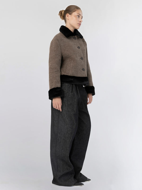 A model showcases a stylish brown cropped jacket with a black fur collar, paired with wide-leg dark trousers by MEOTINE.