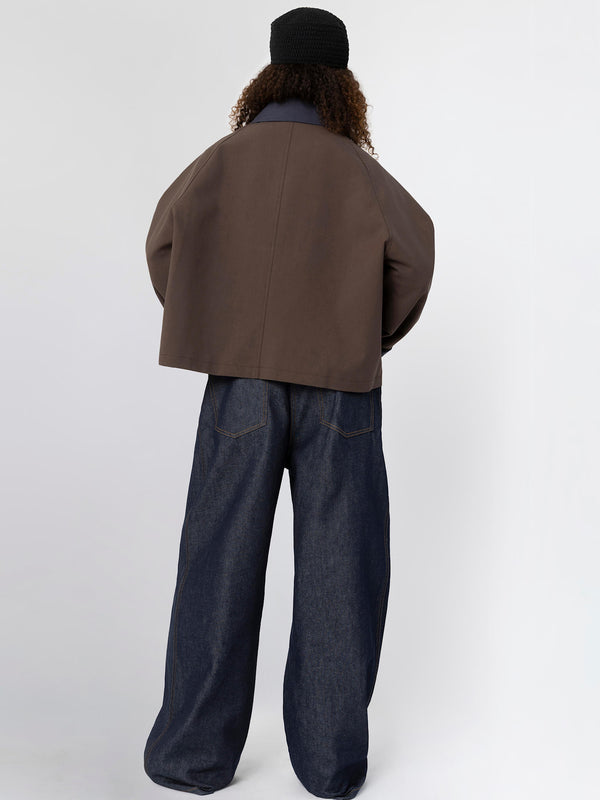 A model wearing a brown oversized jacket and wide-leg denim jeans, showcasing a stylish, contemporary look by MEOTINE.