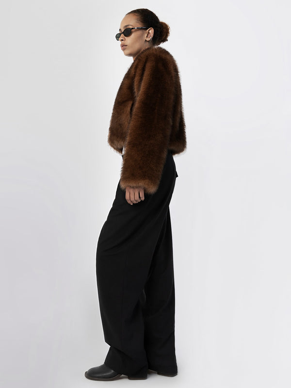 A model showcases a chic brown faux fur jacket paired with wide-leg black trousers, exuding a stylish vibe for MEOTINE.