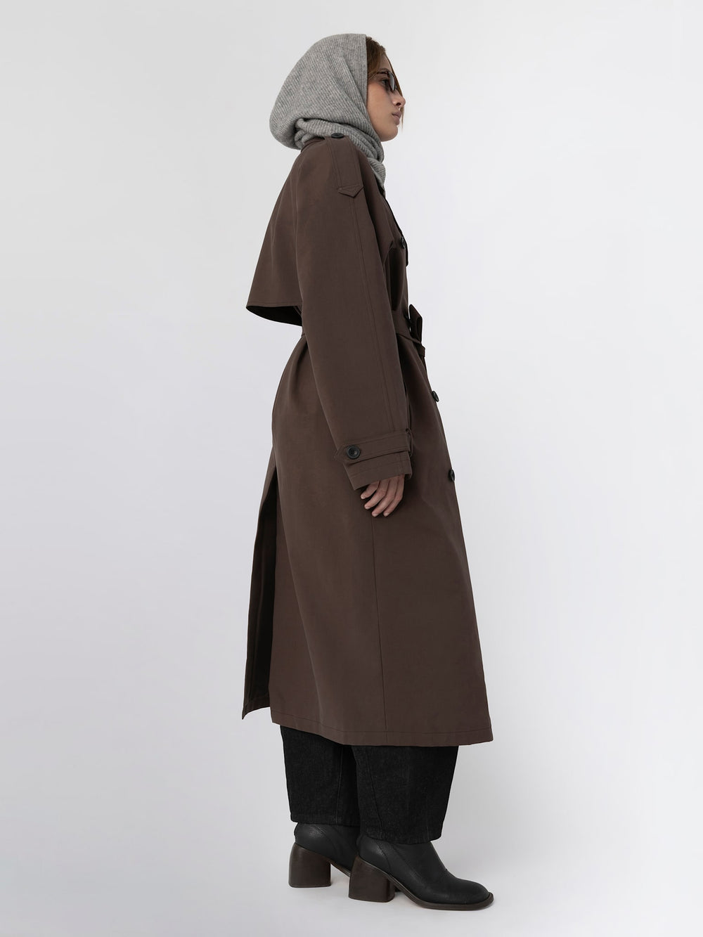 A model wearing a brown trench coat with a belt, paired with a gray scarf and sunglasses, showcasing MEOTINE's stylish outerwear.