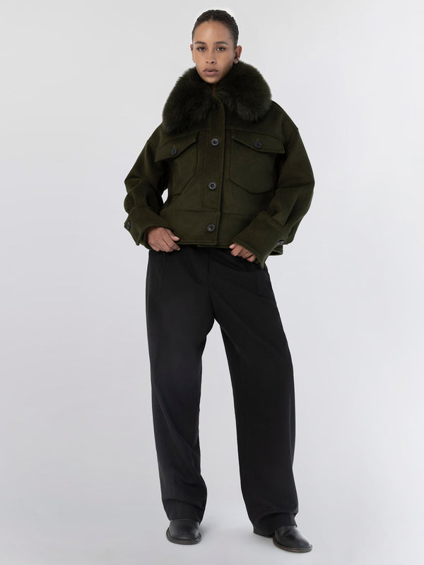 A model showcases a stylish olive green jacket with a fur collar, paired with loose black trousers, embodying MEOTINE's chic aesthetic.