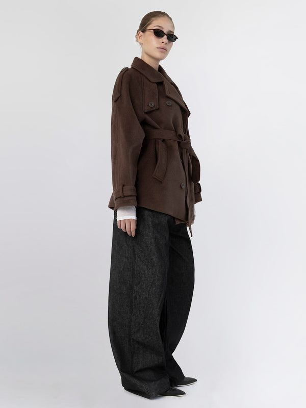A model showcases a stylish brown trench coat with a belt, paired with oversized black pants and sunglasses, representing MEOTINE's chic aesthetic.