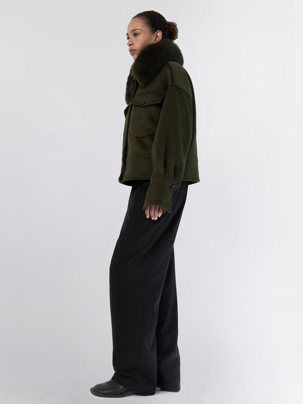 A model showcases a stylish olive green jacket with a fur collar, paired with wide-leg black trousers, embodying MEOTINE's chic aesthetic.